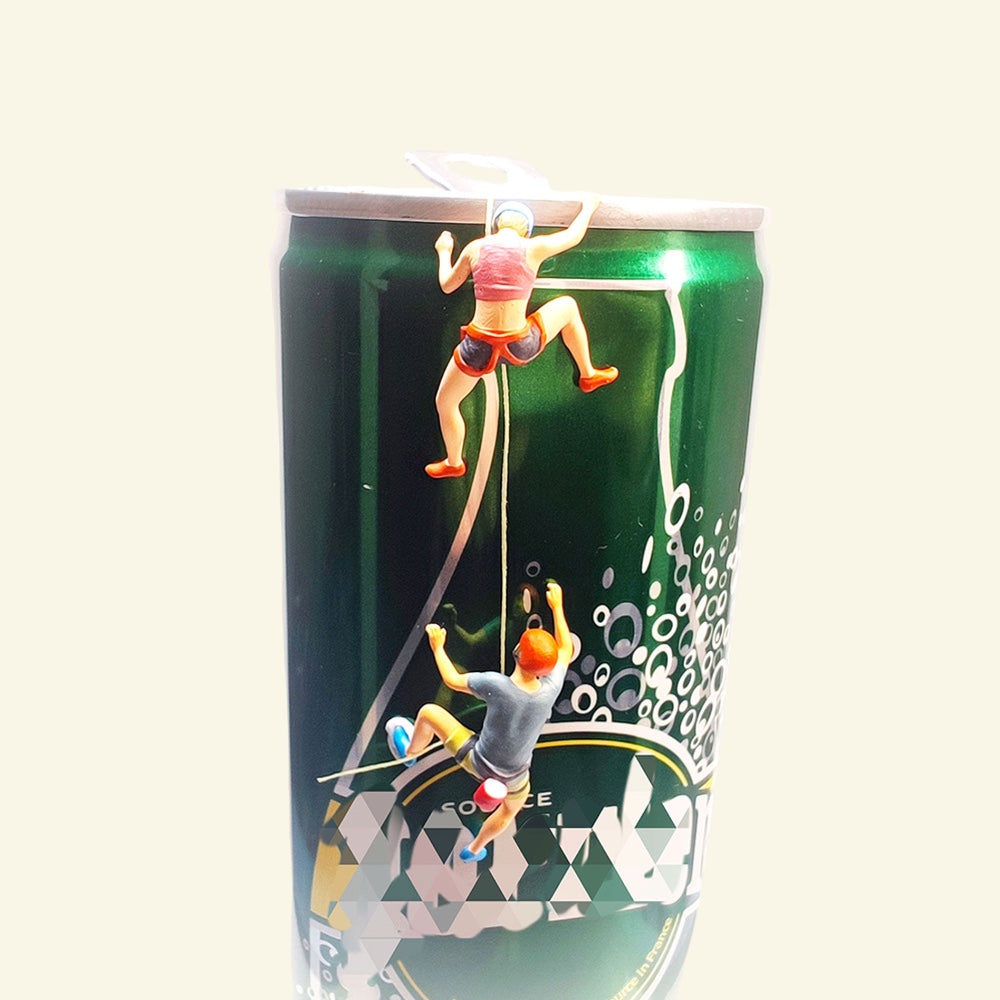 front view of both 1:64 climbers on a green prop can, the woman in a pink top near the rim, the man in an orange helmet and grey shirt further down the thread