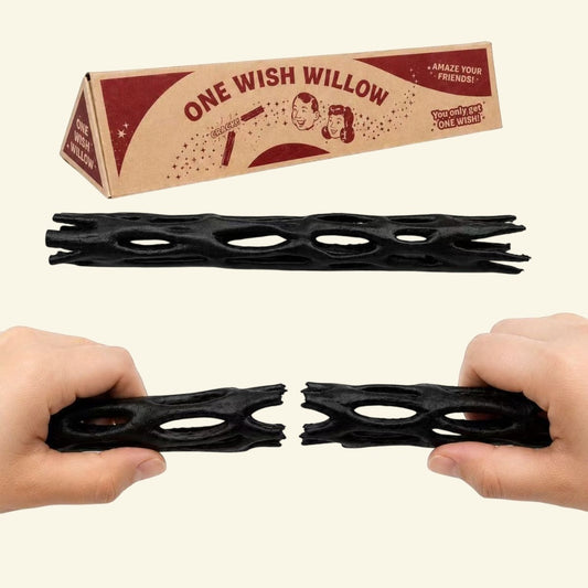 two hands snapping a black one wish willow stick apart, box behind