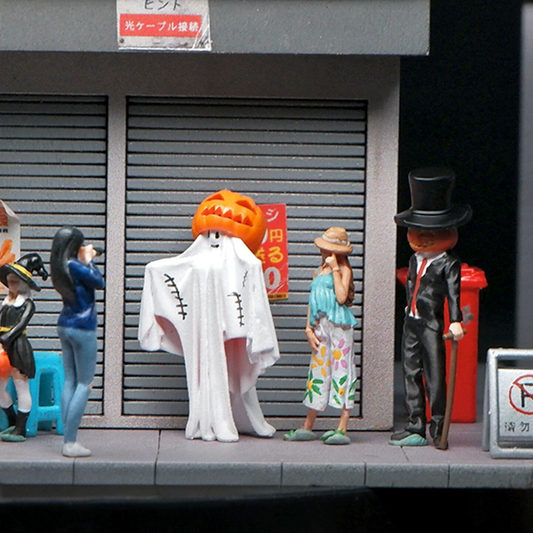 a 1:64 pumpkin-head ghost and a top-hat gentleman standing in front of a closed shop shutter with other tiny people on a miniature street