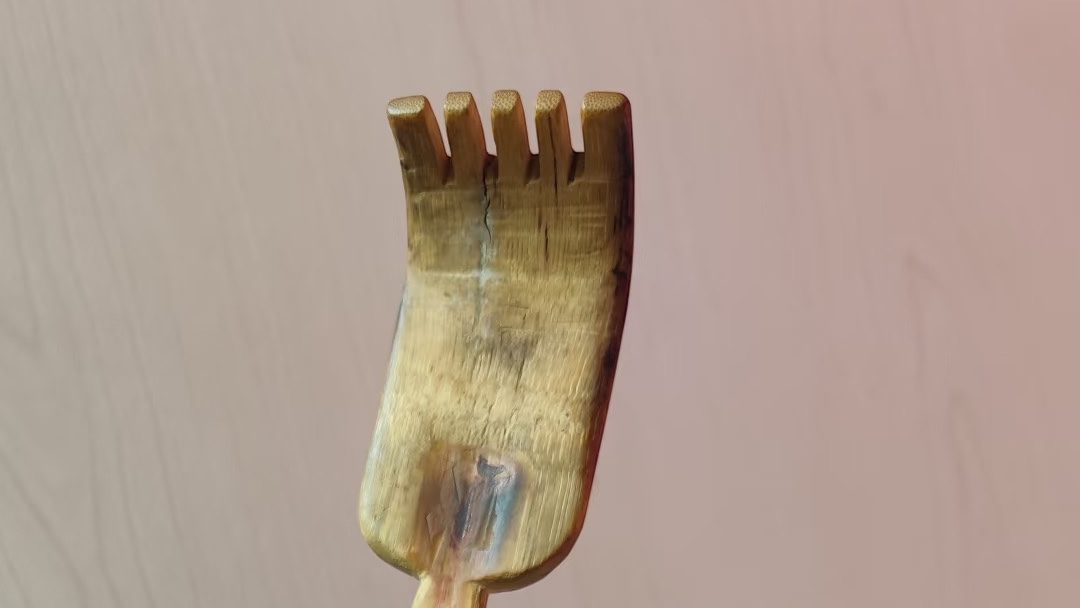 close-up of a worn bamboo back scratcher head with five carved fingers