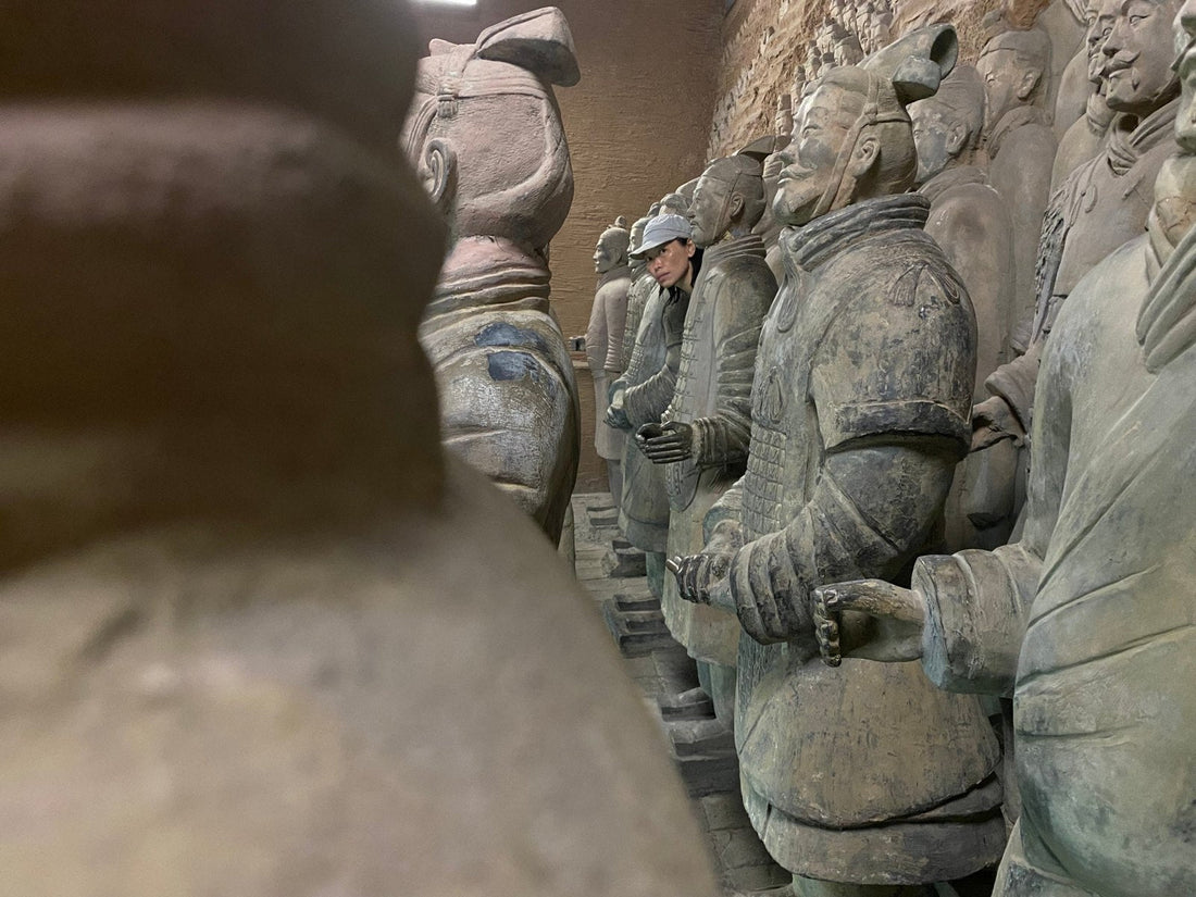 gobby peeking out between rows of replica terracotta warriors at a photo spot in xi'an