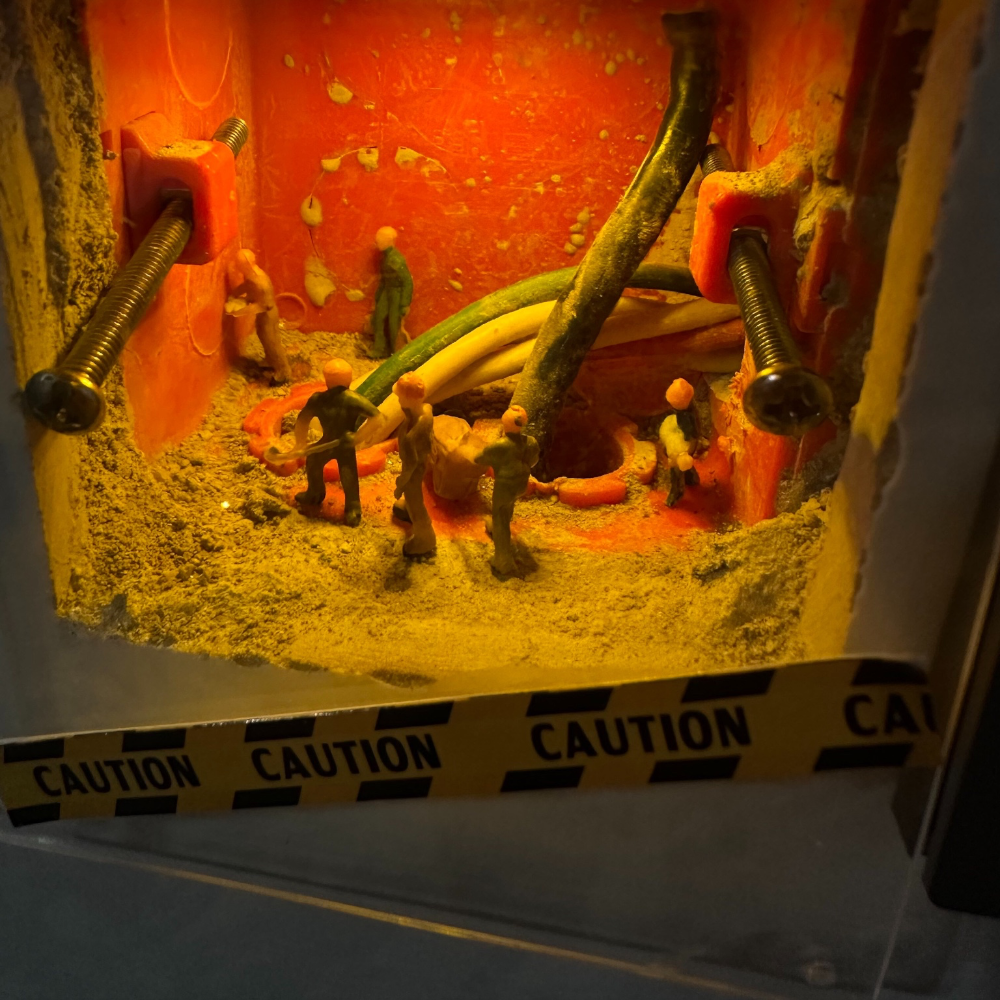 orange-lit switch box with long screws still in place, 1:87 workers walking among the cables