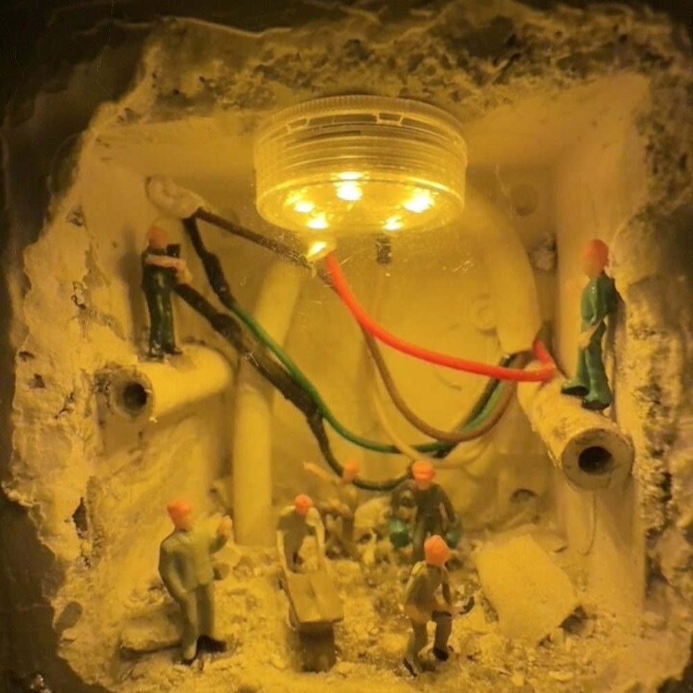 round led light glowing inside a wall hole while 1:87 workers stand among pipes and red and green wires