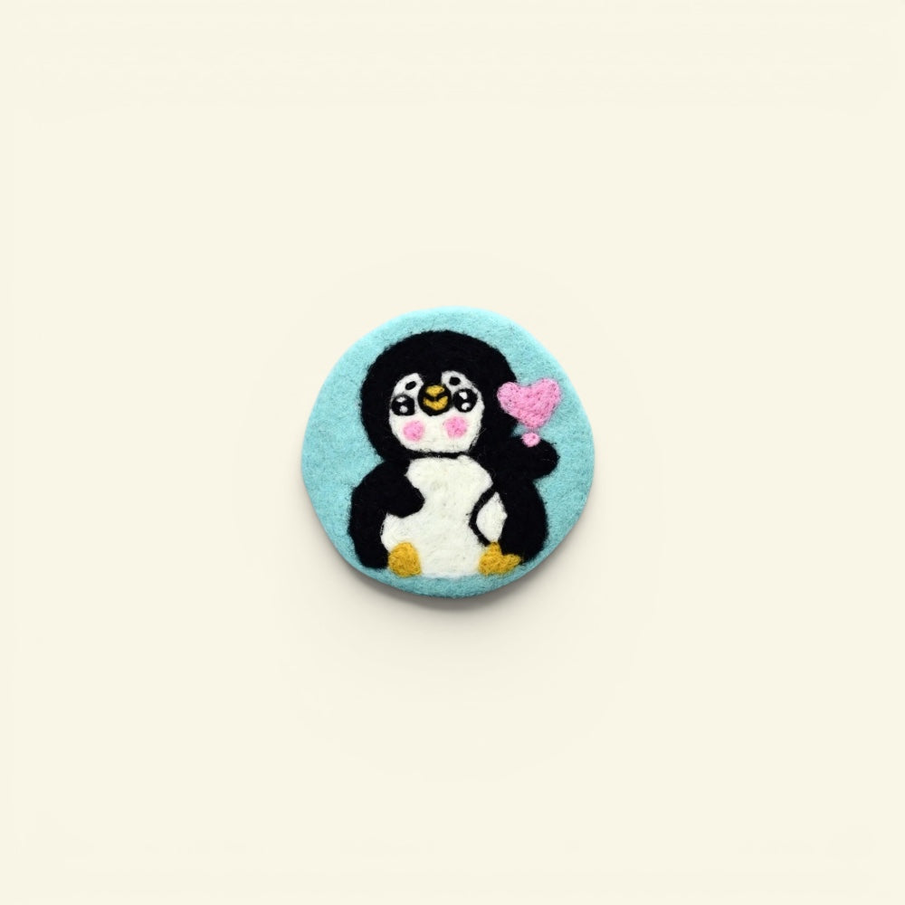 handmade wool felt penguin coaster, teal colorway — embroidered penguin holding a heart, made in nepal