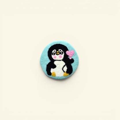 handmade wool felt penguin coaster, teal colorway — embroidered penguin holding a heart, made in nepal