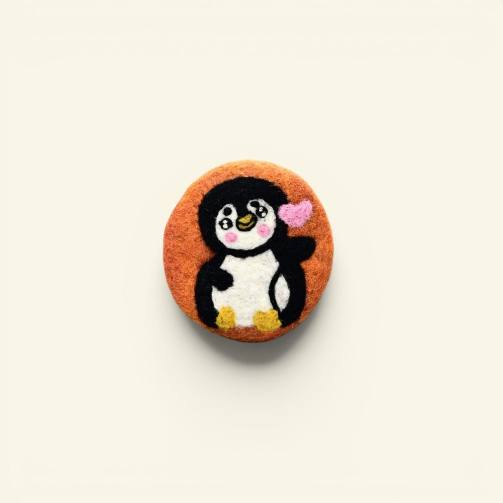 handmade wool felt penguin coaster, orange colorway — embroidered penguin holding a heart, made in nepal