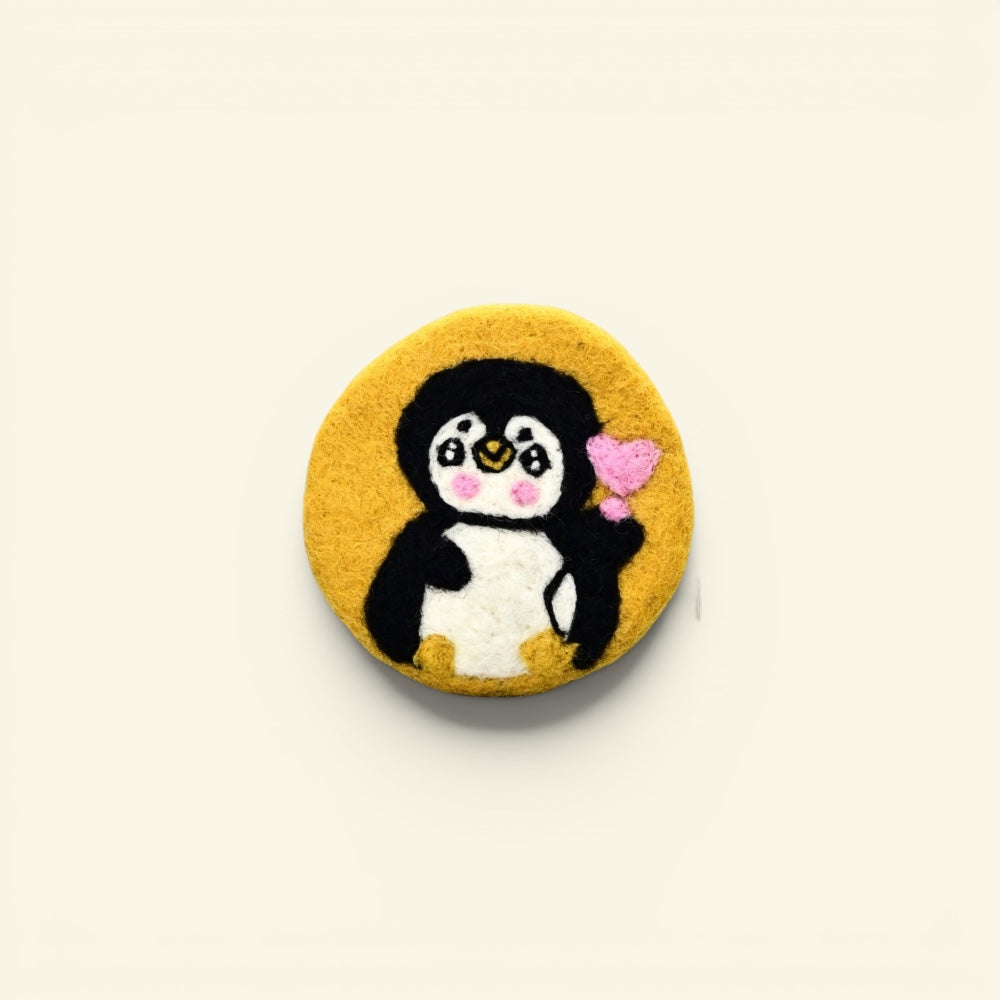 handmade wool felt penguin coaster, yellow colorway — embroidered penguin holding a heart, made in nepal
