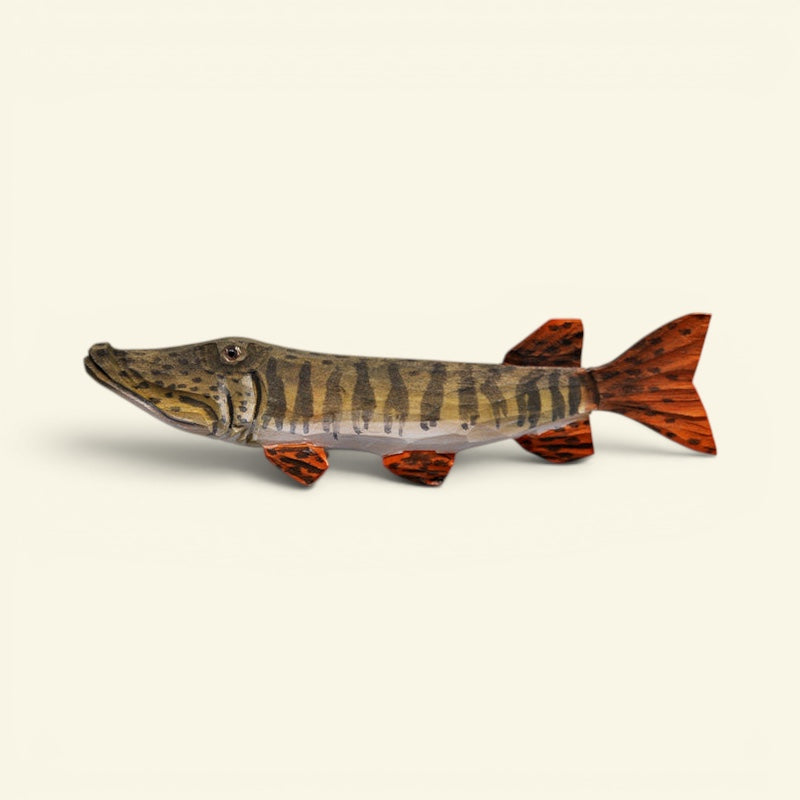 A decorative wooden fish sculpture of a northern pike, featuring realistic brown and black vertical stripes on its body and vibrant orange-brown fins, set against a solid cream background. uggaz