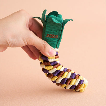 Hand holding The Knot Harvest corn rope toy, showing the husk-leaf detail