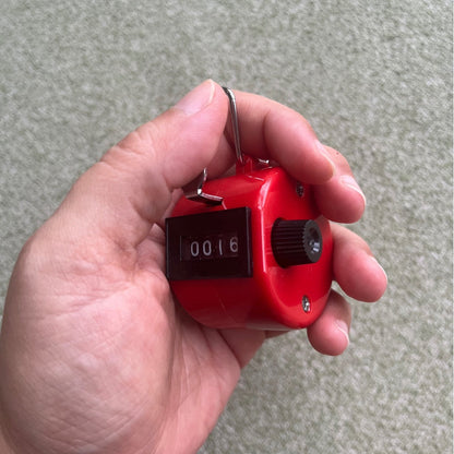 the tally counter – red, held in hand mid-count at 0016, uggaz