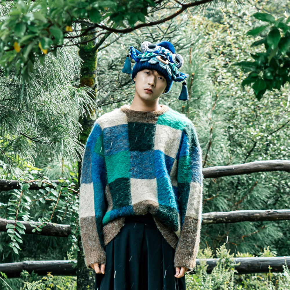 the ox head beanie in blue worn in a misty forest with a wooden fence in the background, uggaz