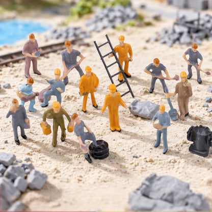 the 25-piece worker set placed on a sandy model railway scene, workers shovelling next to the ladder and cart