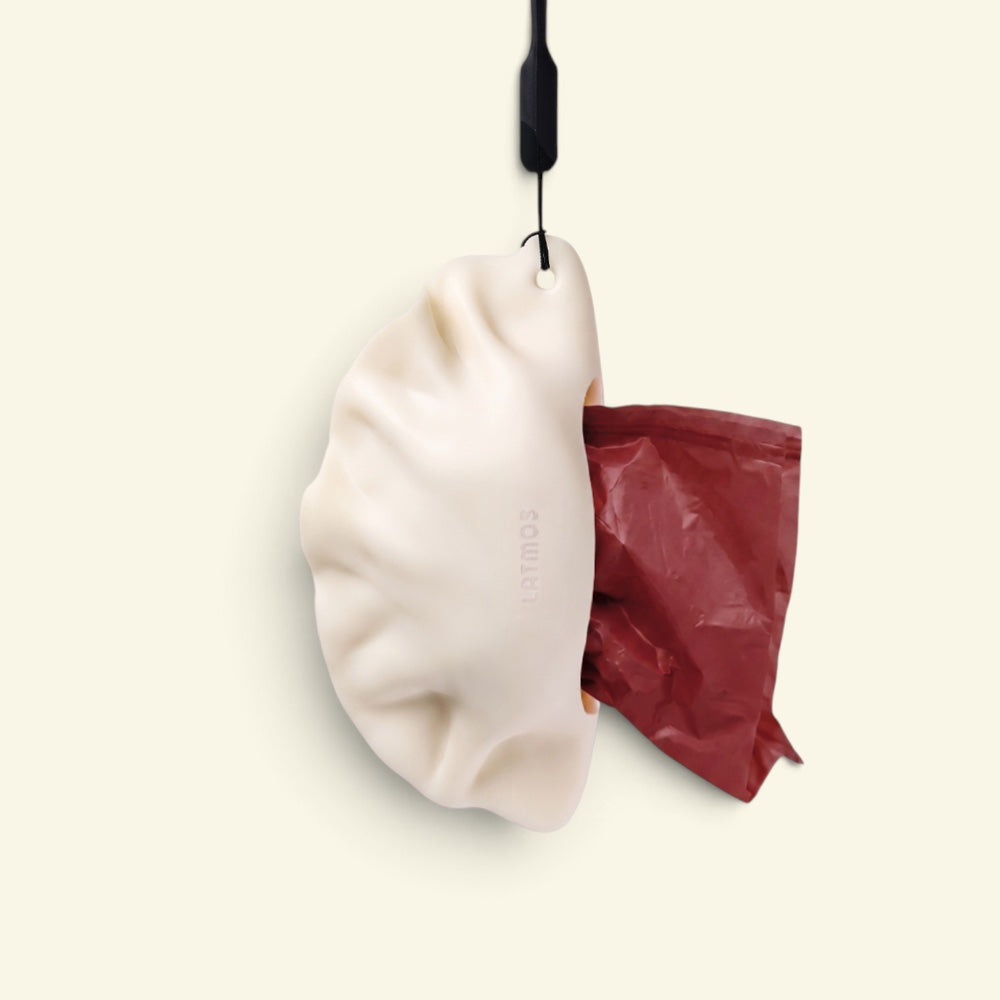 the dumpling silicone poop bag dispenser, open with a maroon bag showing