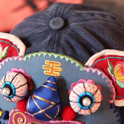 close-up of the tiger head cap's crown button and top of the tiger face, bead eyes and floral ear visible, uggaz