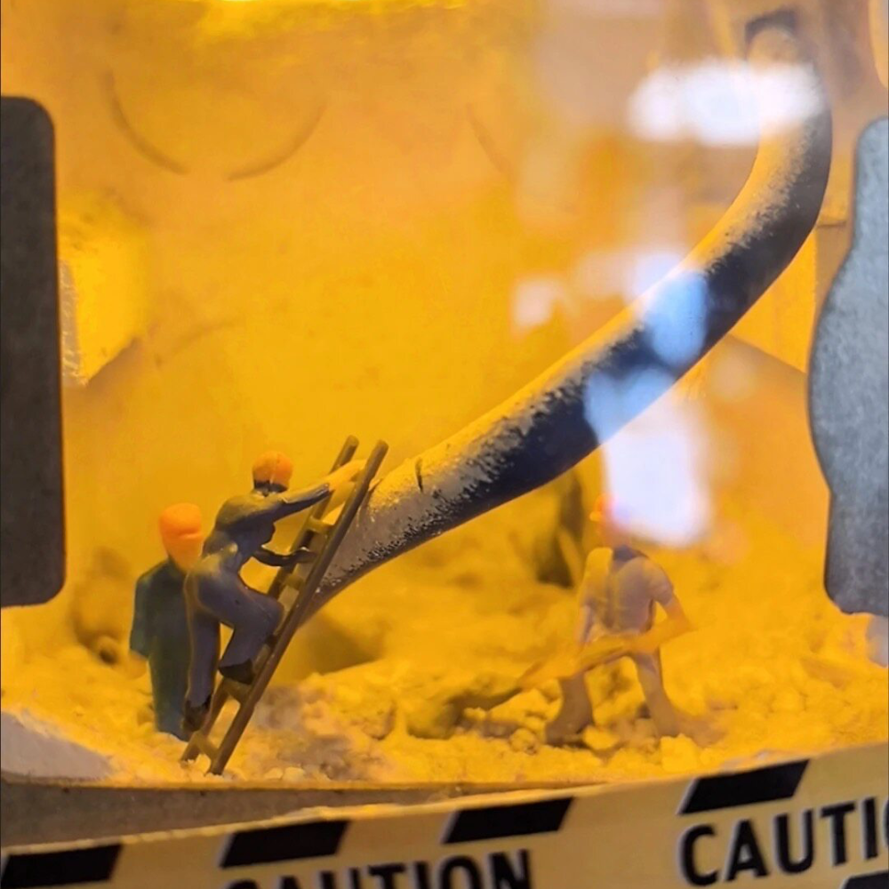 close-up of a 1:87 worker climbing a ladder up a thick cable inside a wall, lit yellow