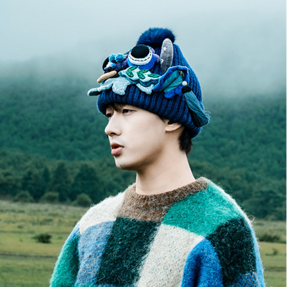 the ox head beanie in blue worn at a three-quarter angle, foggy mountain landscape, uggaz
