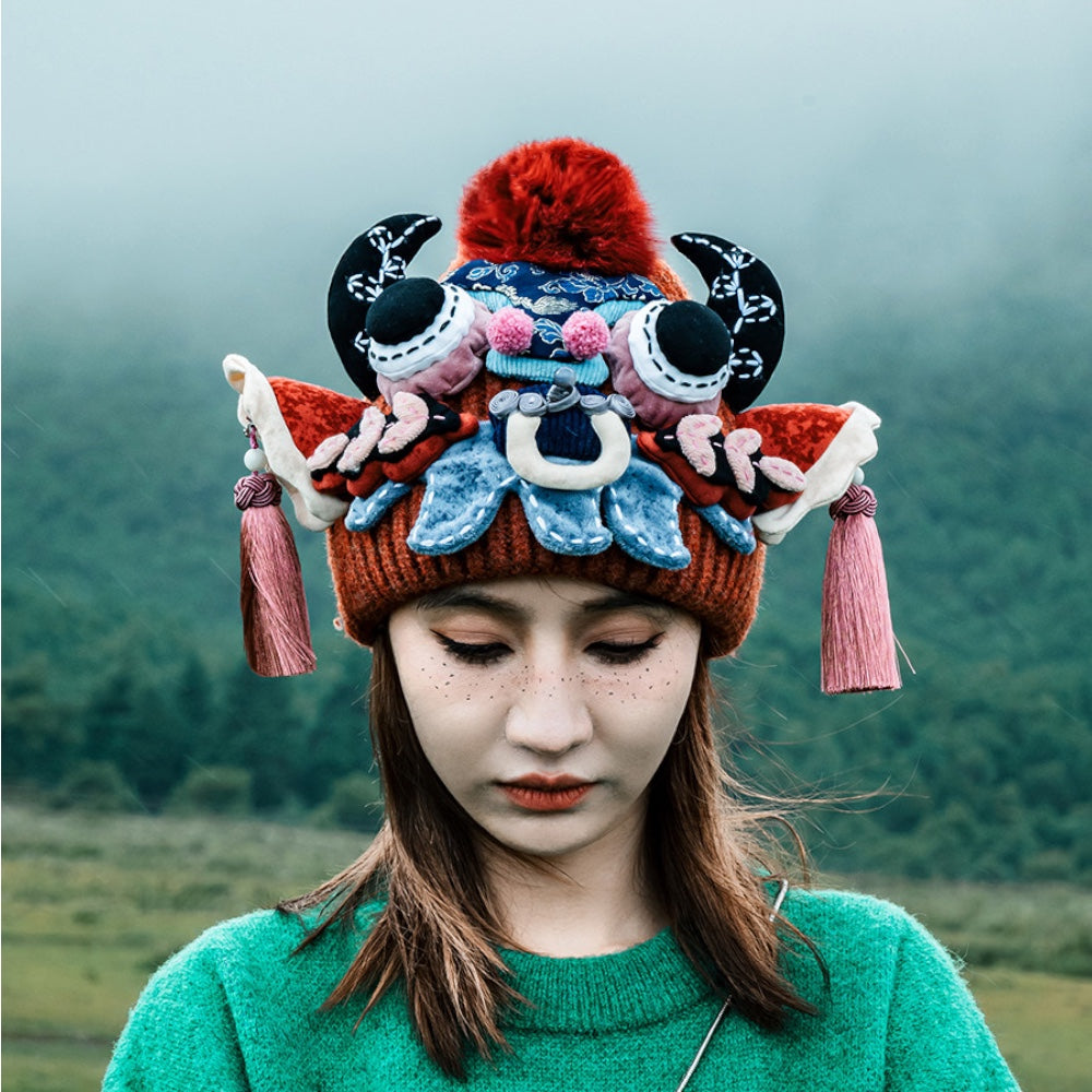 the ox head beanie in red worn outdoors, close detail against a foggy mountain landscape, uggaz