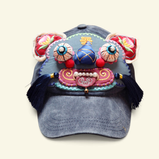 the tiger head cap on a plain background — gray denim ballcap with an embroidered tiger face, bead eyes, blue nose, and navy tassels, uggaz
