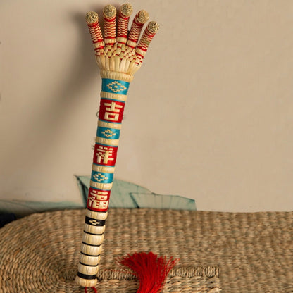 the sorghum hand standing upright on a woven mat with its red tassel visible, uggaz