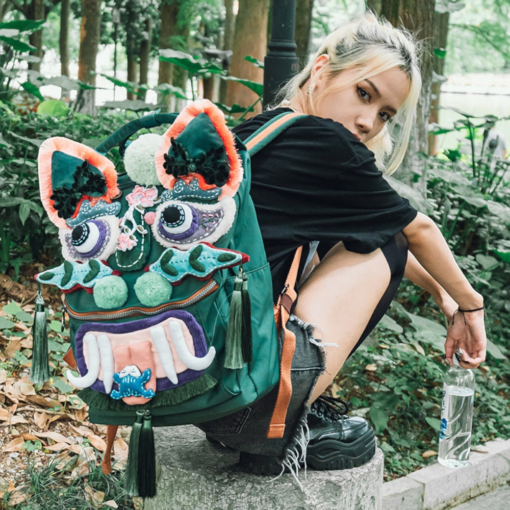the tiger pack worn outdoors in a park, full tiger face and tassels visible as the wearer crouches on a stone post, uggaz