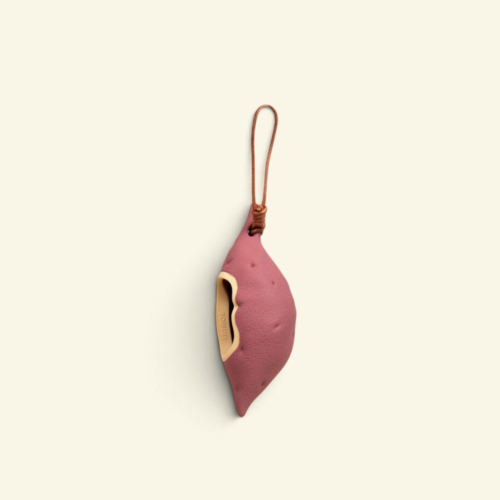 the yam sweet-potato-shaped silicone poop bag dispenser with leather hanging strap, studio shot