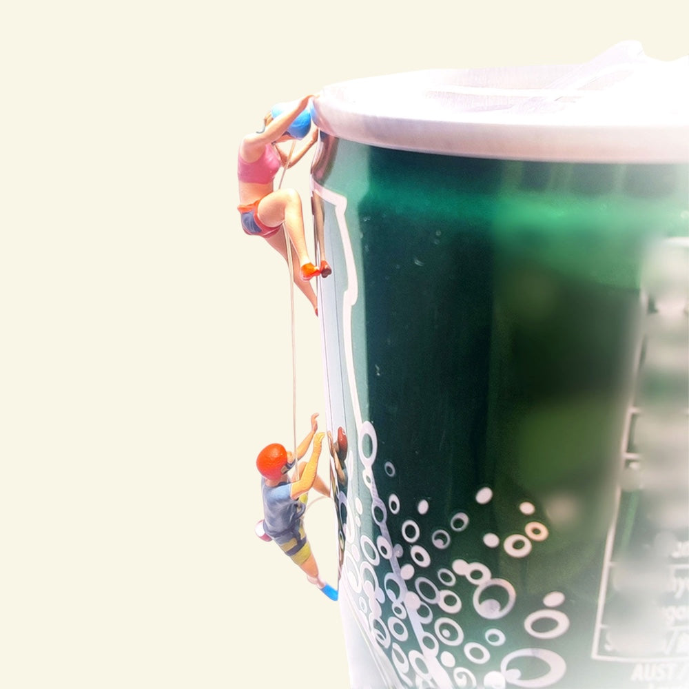 the pair of 1:64 rock climbers near the top of a green prop can, blue helmet climbing above orange helmet, joined by a thin thread