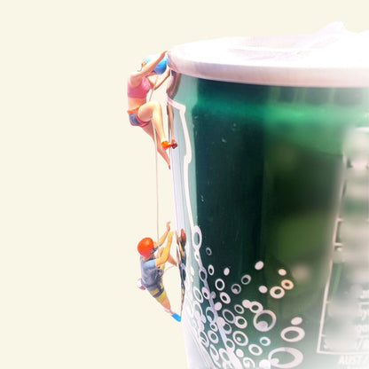 the pair of 1:64 rock climbers near the top of a green prop can, blue helmet climbing above orange helmet, joined by a thin thread