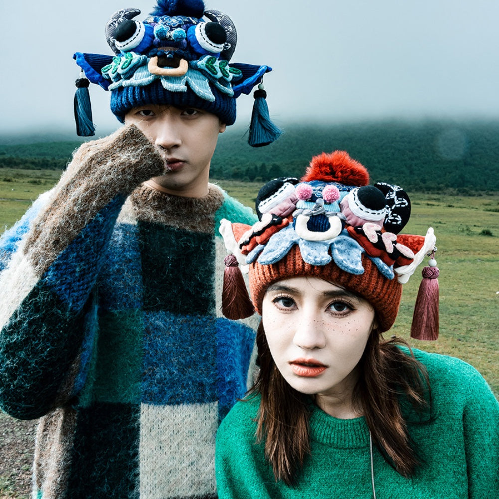 a couple in a grassy field, one wearing the blue ox head beanie and the other the red version, uggaz