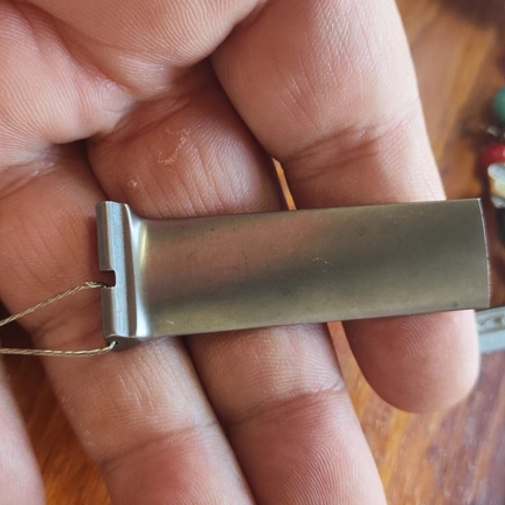 an unmarked ch-47 chinook t55 compressor blade keychain held flat in a palm, steel wire threaded through the root