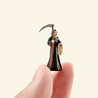 the 1:64 reaper held between two fingers, showing how small he is next to a fingertip