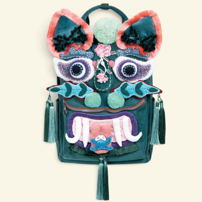the tiger pack backpack on a plain background — forest green canvas with a full tiger-face appliqué, peach-fringed ears, mint pom cheeks, and tassels on both sides, uggaz