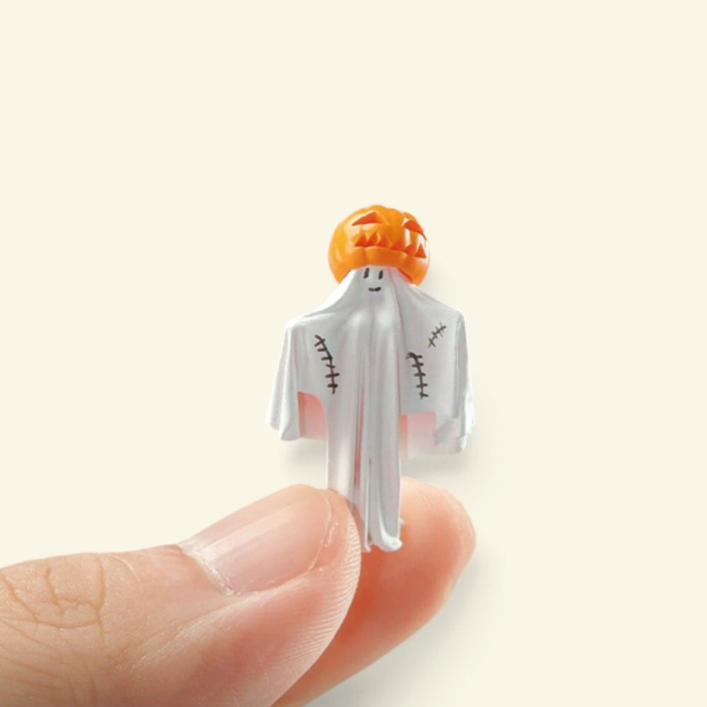 the 1:64 pumpkin-head ghost standing on a fingertip, showing how small it is