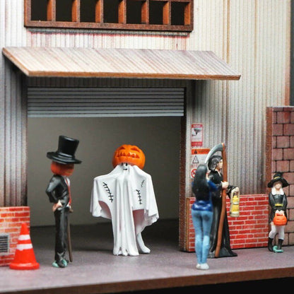 1:64 halloween figures outside a miniature shop with a rolled-up shutter, next to a tiny traffic cone and a brick wall