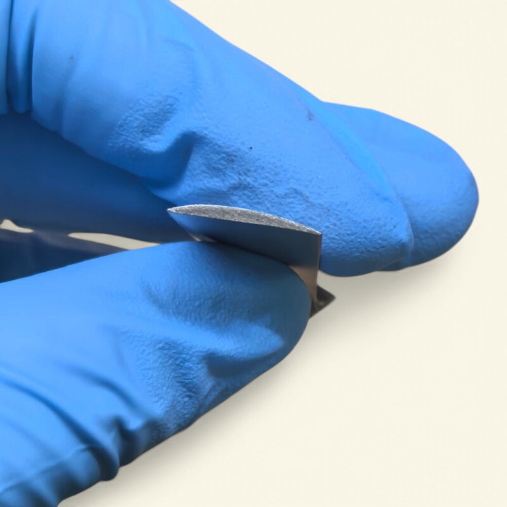 gloved fingers showing the blade edge-on, thinning out toward the tip