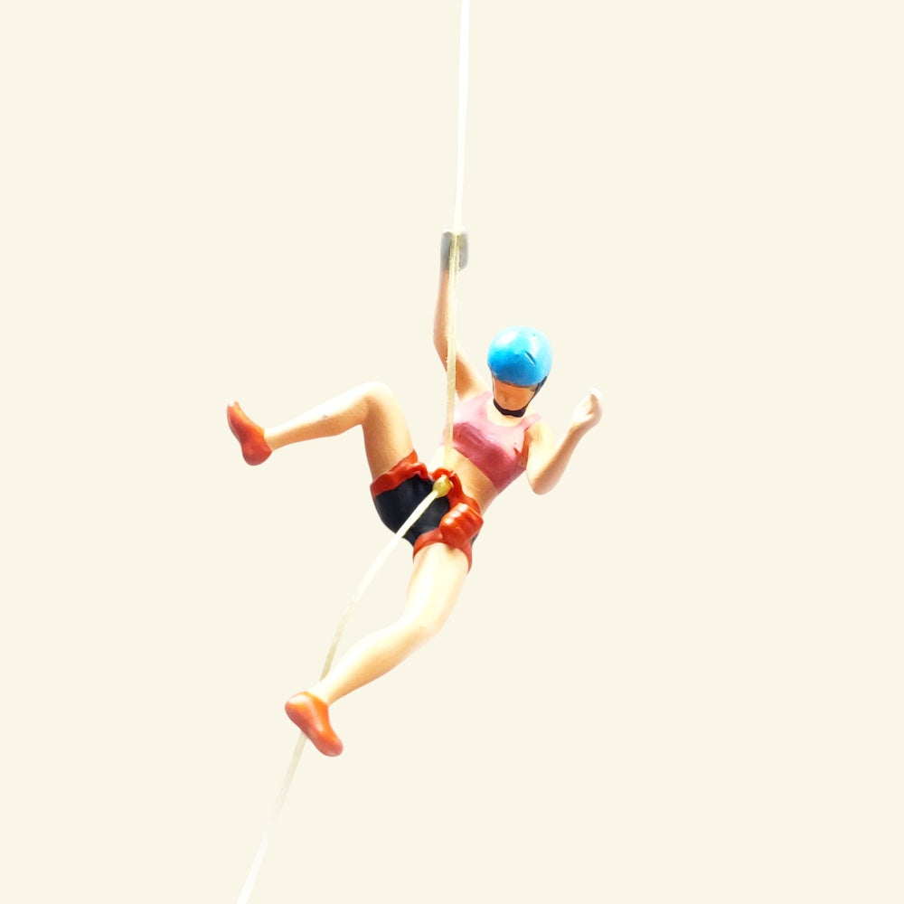 the blue helmet climber: a 1:64 hand-painted woman in a pink top, black shorts and orange harness, leaning back on a thread with one leg kicked out