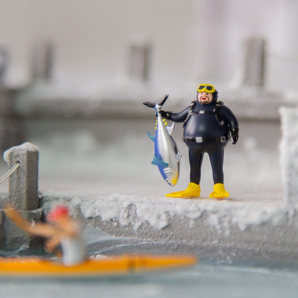 the diver holding a tuna on a snowy 1:64 dock diorama, a kayaker blurred in front (diorama not included)