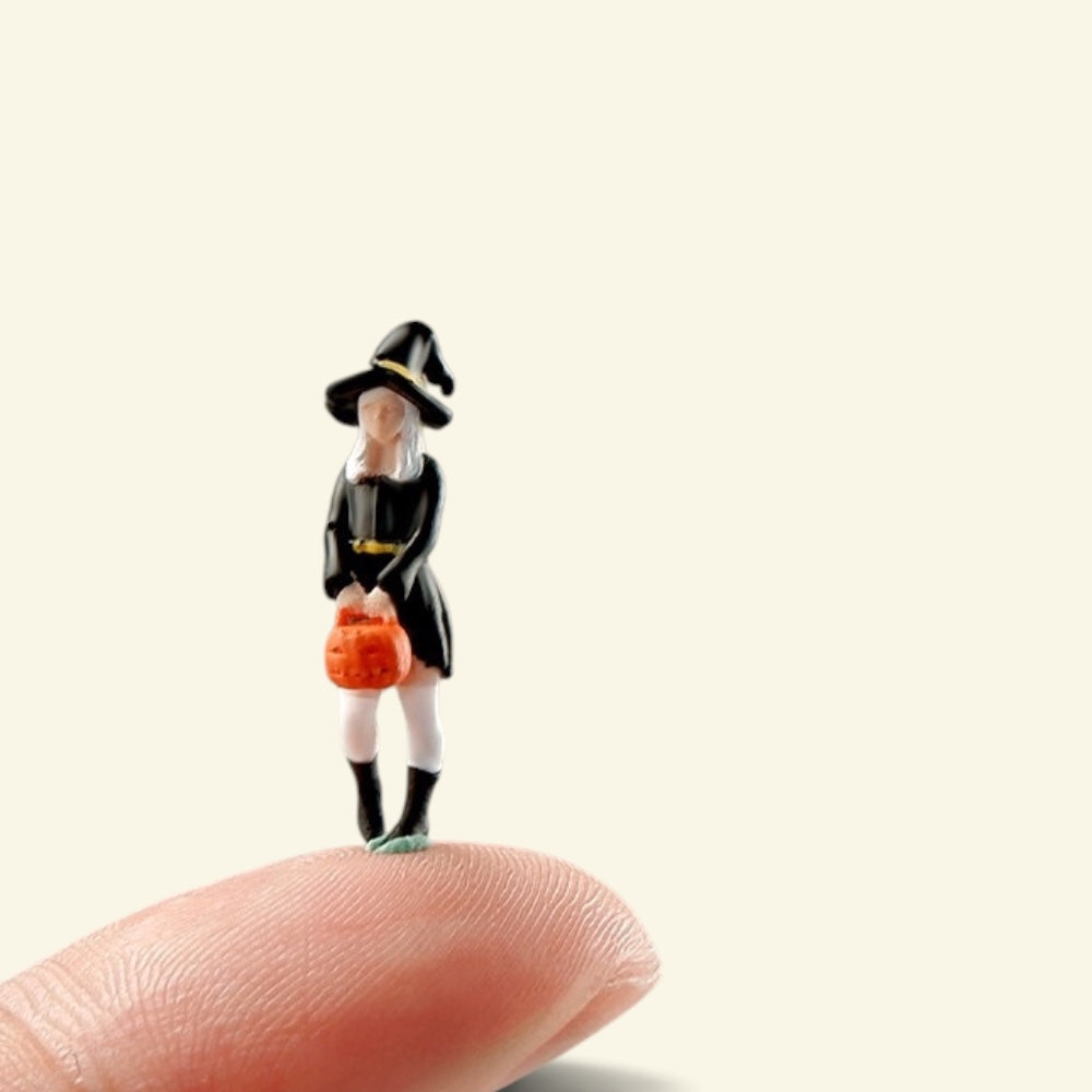 the 1:64 little witch standing on a fingertip, about 0.9 in tall