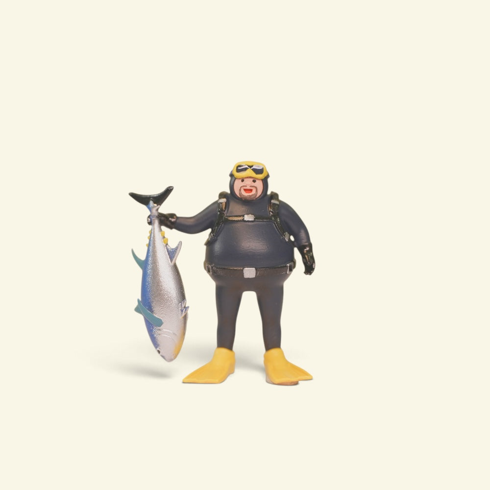 front view of the 1:64 diver figure: yellow goggles, black wetsuit, yellow fins, tuna held by the tail