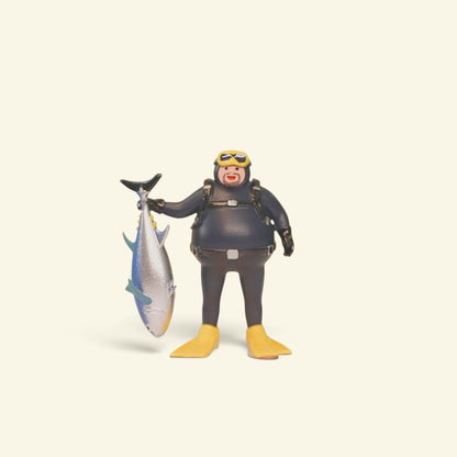 front view of the 1:64 diver figure: yellow goggles, black wetsuit, yellow fins, tuna held by the tail