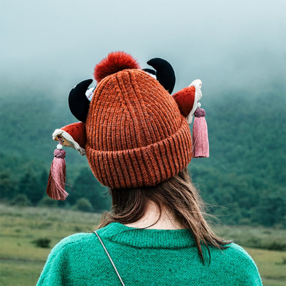 the ox head beanie in red from behind, showing the horns and tassels over a foggy field, uggaz