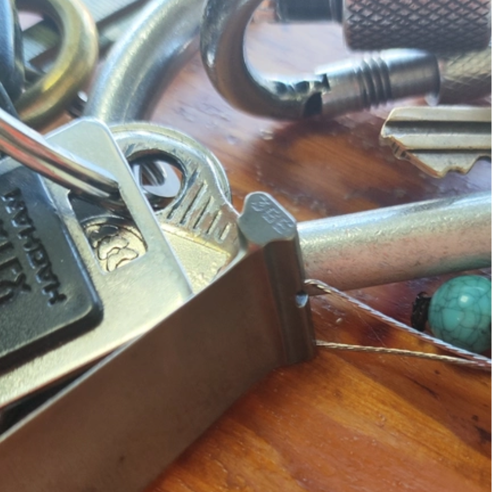 the turbine blade keychain clipped onto a ring of car keys and a carabiner on a wooden table