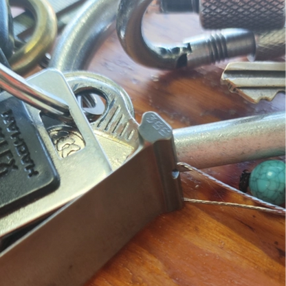 the turbine blade keychain clipped onto a ring of car keys and a carabiner on a wooden table