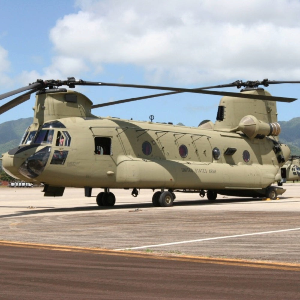 a ch-47 chinook twin-rotor helicopter parked on a flight line