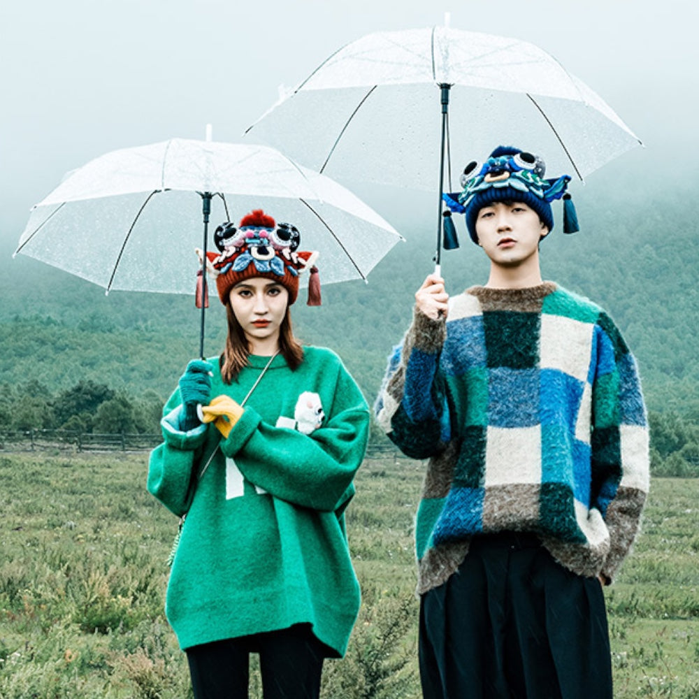 a couple standing under umbrellas in a misty field, wearing the red and blue ox head beanies, uggaz