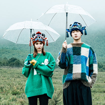 a couple standing under umbrellas in a misty field, wearing the red and blue ox head beanies, uggaz