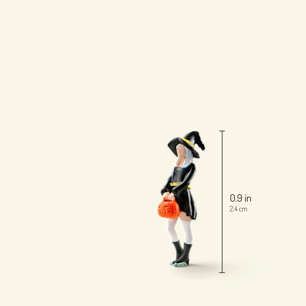 the little witch, a 1:64 figure in a pointed black hat and dress carrying an orange pumpkin bucket, about 0.9 in / 2.4 cm tall